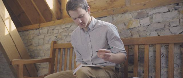 a Carroll University student sitting 和 writing on a notepad.